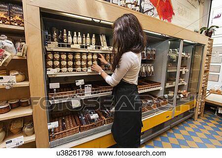 Stock Photo - Portrait of smiling saleswoman arranding products in supermarket. Fotosearch