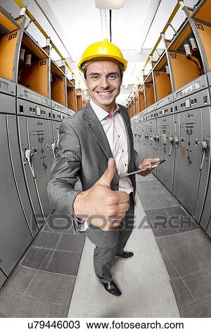 Stock Image - Portrait of smiling supervisor with tablet PC gesturing thumbs up in control room. Fotosearch