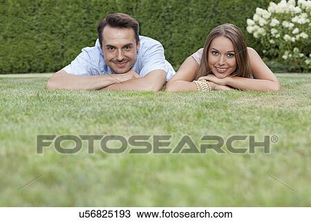 Portrait of smiling young couple relaxing on grass in park View Large Photo Image Stock Image - Portrait of smiling young couple relaxing on grass in park. Fotosearch