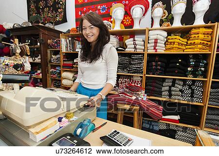 Portrait of smiling young female salesperson at checkout stand in gift store View Large Photo Image Stock Image - Portrait of smiling young female salesperson at checkout stand in gift store. Fotosearch