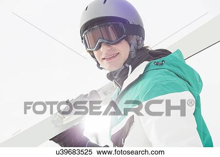 Portrait of smiling young man carrying skis against clear sky View Large Photo Image Stock Photography - Portrait of smiling young man carrying skis against clear sky. Fotosearch