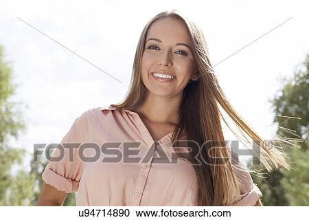 Portrait of smiling young woman in park View Large Photo Image Stock Image - Portrait of smiling young woman in park. Fotosearch