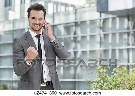 Portrait of successful young businessman using cell phone against office building View Large Photo Image Stock Image - Portrait of successful young businessman using cell phone against office building. Fotosearch
