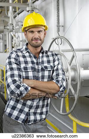 Portrait of worker with arms crossed leaning on large valve in industry View Large Photo Image Stock Image - Portrait of worker with arms crossed leaning on large valve in industry. Fotosearch
