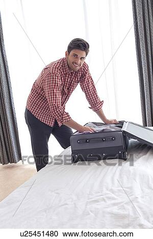 Portrait of young businessman unpacking suitcase in hotel room View Large Photo Image Stock Image - Portrait of young businessman unpacking suitcase in hotel room. Fotosearch