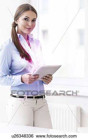 Portrait of young businesswoman using digital tablet in office View Large Photo Image Stock Photograph - Portrait of young businesswoman using digital tablet in office. Fotosearch