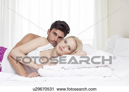 Portrait of young couple lying in bed View Large Photo Image Stock Image - Portrait of young couple lying in bed. Fotosearch