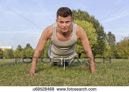 Stock Photo - Portrait of young man doing pushups in park. Fotosearch