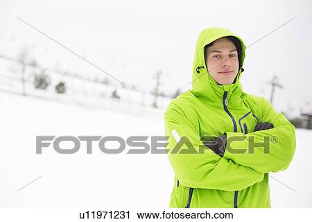 Portrait of young man in hooded jacket standing arms crossed in snow View Large Photo Image Stock Image - Portrait of young man in hooded jacket standing arms crossed in snow. Fotosearch