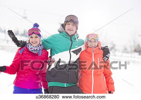 Stock Image - Portrait of young man with female friends enjoying in snow. Fotosearch