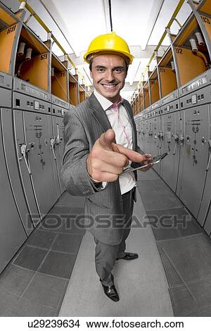 Portrait of young smiling supervisor with tablet PC pointing at you in control room View Large Photo Image Picture - Portrait of young smiling supervisor with tablet PC pointing at you in control room. Fotosearch