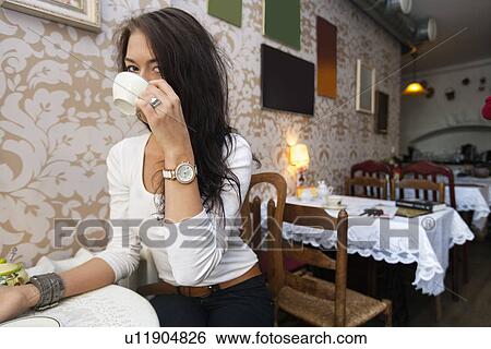 Portrait of young woman drinking coffee at cafe View Large Photo Image Stock Photograph - Portrait of young woman drinking coffee at cafe. Fotosearch