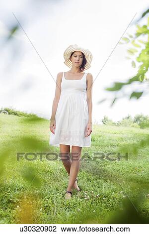 Portrait of young woman in sundress and hat walking in park View Large Photo Image Stock Image - Portrait of young woman in sundress and hat walking in park. Fotosearch