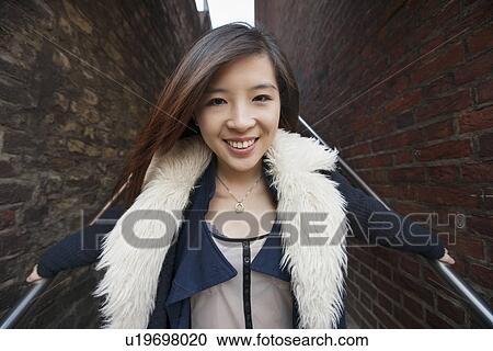 Stock Image - Portrait of young woman smiling on steps at London, England, UK. Fotosearch