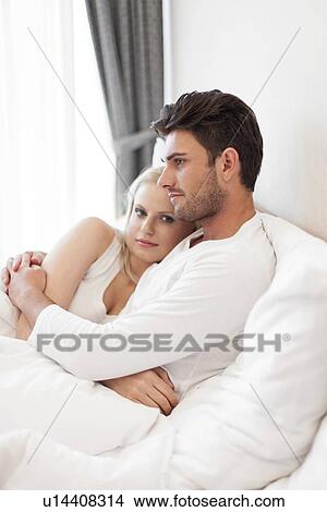 Picture - Portrait of young woman with man hugging in hotel room. Fotosearch
