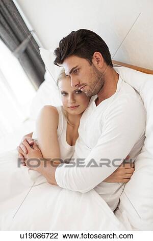 Stock Image - Portrait of young woman with man embracing in hotel room. Fotosearch