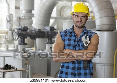 Portrait of young worker standing arms crossed in industry View Large Photo Image Stock Image - Portrait of young worker standing arms crossed in industry. Fotosearch