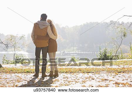 Rear view of couple looking at lake in park during autumn View Large Photo Image Stock Image - Rear view of couple looking at lake in park during autumn. Fotosearch