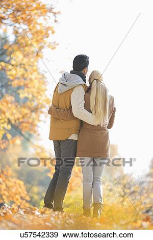 Rear view of couple looking at view in park during autumn View Large Photo Image Stock Photo - Rear view of couple looking at view in park during autumn. Fotosearch