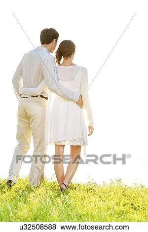 Rear view of couple standing arms around against clear sky View Large Photo Image Stock Photo - Rear view of couple standing arms around against clear sky. Fotosearch