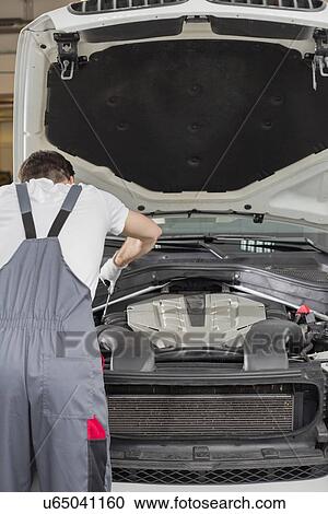 Rear view of male engineer repairing car in automobile repair shop View Large Photo Image Stock Image - Rear view of male engineer repairing car in automobile repair shop. Fotosearch