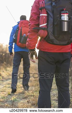 Stock Photo - Rear view of male hikers in field. Fotosearch