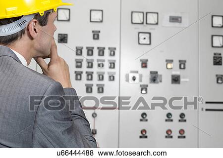 Rear view of male supervisor examining control room in industry View Large Photo Image Stock Photo - Rear view of male supervisor examining control room in industry. Fotosearch