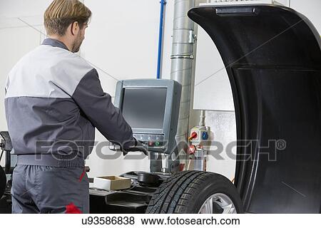Rear view of mid adult automobile mechanic working in workshop View Large Photo Image Stock Photo - Rear view of mid adult automobile mechanic working in workshop. Fotosearch