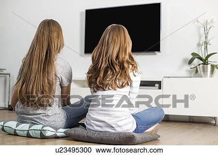 Rear view of siblings watching TV at home View Large Photo Image Stock Image - Rear view of siblings watching TV at home. Fotosearch