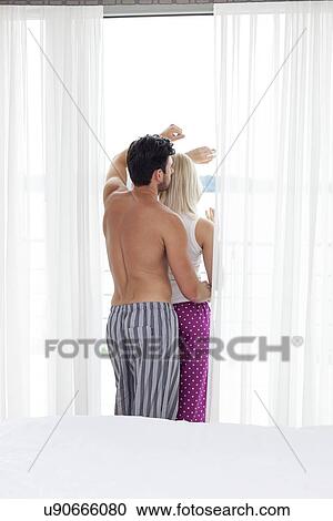 Rear view of young couple looking through window of hotel room View Large Photo Image Stock Image - Rear view of young couple looking through window of hotel room. Fotosearch