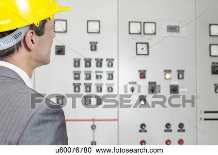 Rear view of young male supervisor examining control room in industry View Large Photo Image Stock Image - Rear view of young male supervisor examining control room in industry. Fotosearch