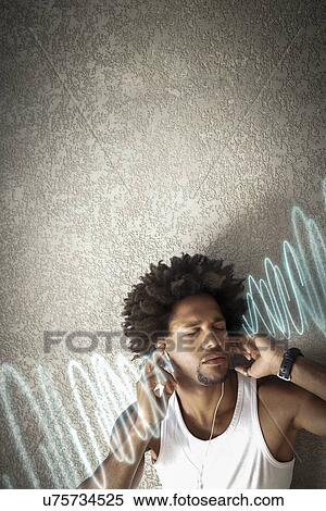 Relaxed young man listening music while leaning on wall View Large Photo Image Stock Photography - Relaxed young man listening music while leaning on wall. Fotosearch
