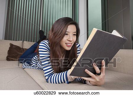 Relaxed young woman reading book at home View Large Photo Image Stock Photo - Relaxed young woman reading book at home. Fotosearch
