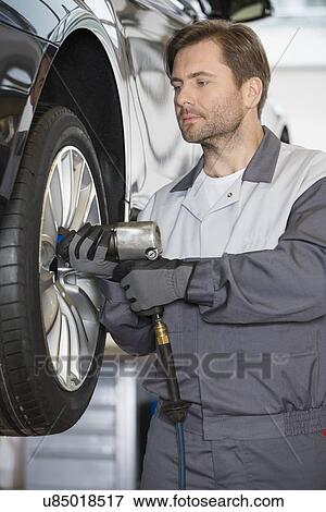 Stock Photo - Repairman adjusting car's wheel in workshop. Fotosearch