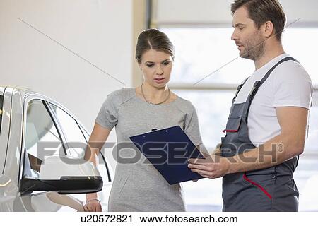 Repairman holding clipboard while conversing with female customer in repair shop View Large Photo Image Stock Image - Repairman holding clipboard while conversing with female customer in repair shop. Fotosearch