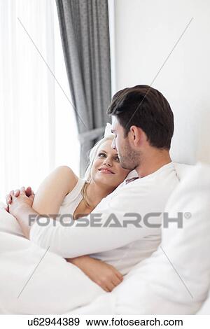 Stock Photo - Romantic young couple embracing in bed. Fotosearch