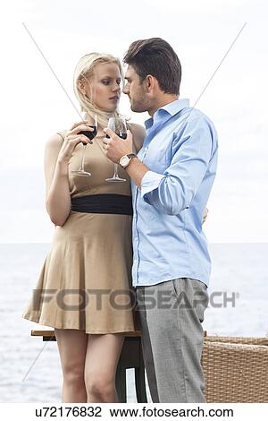 Romantic young couple holding red wine glass at outdoor restaurant by lake View Large Photo Image Stock Image - Romantic young couple holding red wine glass at outdoor restaurant by lake. Fotosearch