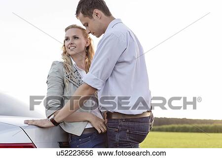 Romantic young couple leaning on back of car at countryside View Large Photo Image Stock Photograph - Romantic young couple leaning on back of car at countryside. Fotosearch