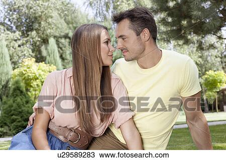Stock Image - Romantic young couple looking at each other in park. Fotosearch