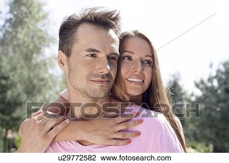Romantic young couple looking away in park View Large Photo Image Stock Image - Romantic young couple looking away in park. Fotosearch