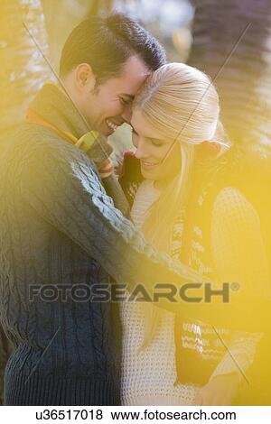 Stock Photo - Romantic young couple smiling in park during autumn. Fotosearch