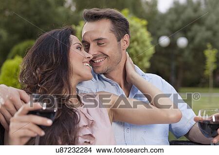 Picture - Romantic young couple with wine glasses in park. Fotosearch