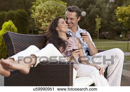 Romantic young holding wine glasses on easy chair in park View Large Photo Image Stock Image - Romantic young holding wine glasses on easy chair in park. Fotosearch