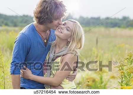 Romantic young man kissing woman in field View Large Photo Image Picture - Romantic young man kissing woman in field. Fotosearch