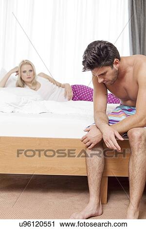 Sad young man on bed with woman in background at hotel room View Large Photo Image Stock Image - Sad young man on bed with woman in background at hotel room. Fotosearch