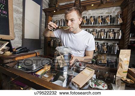 Stock Image - Salesman smelling tea in store. Fotosearch