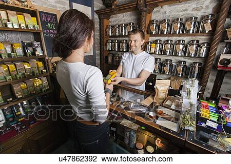 Salesperson giving product to female customer in tea store View Large Photo Image Stock Image - Salesperson giving product to female customer in tea store. Fotosearch