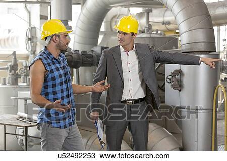 Stock Image - Serious manager showing something to worker in industry. Fotosearch