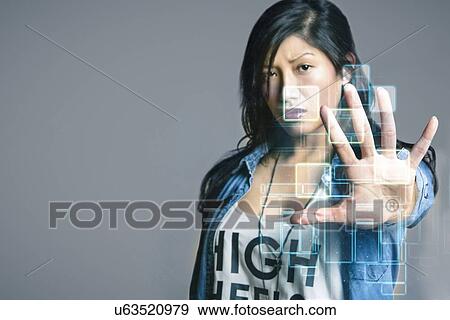Serious mid adult woman touching futuristic computer screen over gray background View Large Photo Image Stock Photo - Serious mid adult woman touching futuristic computer screen over gray background. Fotosearch
