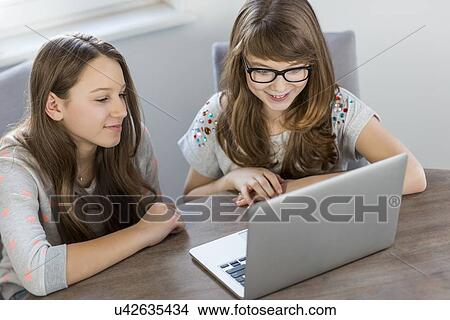 Siblings using laptop together at home View Large Photo Image Picture - Siblings using laptop together at home. Fotosearch